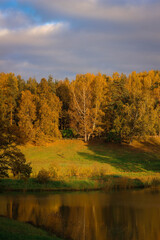 Fototapeta premium Autumn sunny park Landscape. Autumn Trees and River whith a cloudy blue Sky.
