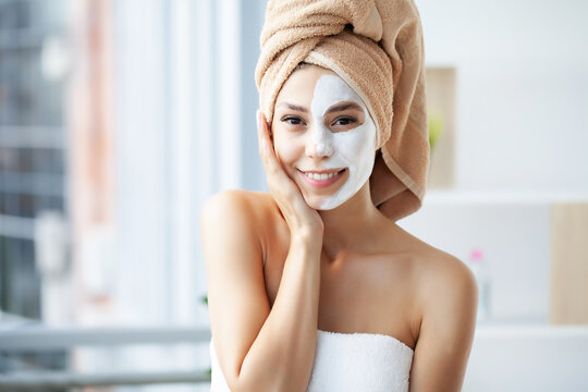 Close-up portrait of beautiful girl with a towel on her head applying facial mask