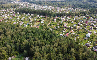Fototapeta na wymiar Beautiful top view of suburban cottages with park and forest. Rural landscape with roofs of small houses and villages