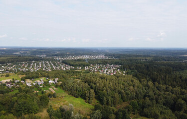 Beautiful top view of suburban cottages with park and forest. Rural landscape with roofs of small houses and villages