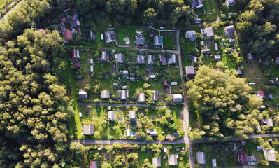 Beautiful top view of suburban cottages with park and forest. Rural landscape with roofs of small houses and villages