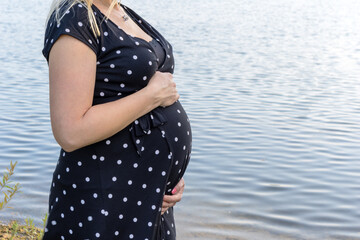 Werdende Mutter mit Babybauch am Ufer eines Sees