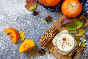Autumn pumpkin spiced latte or coffee in glass with organic ingredients on a light stone countertop. Top view flat lay background. Copy space.