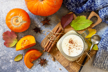Autumn pumpkin spiced latte or coffee in glass with organic ingredients on a light stone countertop. Top view flat lay background.
