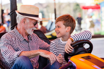 Fototapeta na wymiar Grandfather and grandson hawe fun in bumper car
