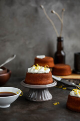 Homemade cupcakes with cream cheese on a small ceramic stand. Food photography on dark backgrounds.