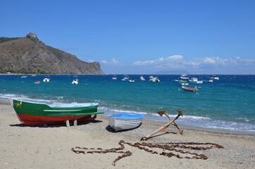 Fototapeta na wymiar Bay of Marinello in Sicily, empty fishing boats on the mediterranean sea and on the beach, view to the Sanctuary of the Madonna on the rock