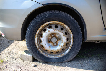 Flat tire, rusted car rim. Car on the street awaiting repair