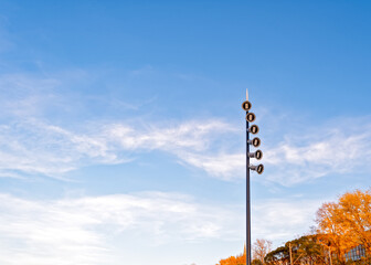 Obraz premium The LED street light is set against a sky with clouds and trees with yellow foliage. Modern street lighting concept.