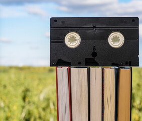 VHS cassette on stack of books. blue sky background. Window frame.