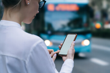 Fototapeta premium Crop focused woman surfing internet on smartphone at bus station