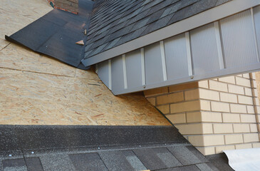 A close-up on unfinished attic roofing construction with fascia board and plywood sheathing covered...