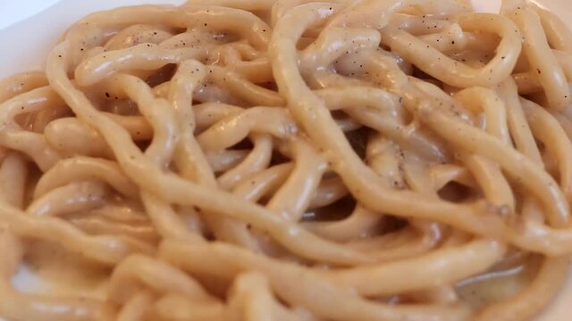 Close-up of homemade Pici noodles with Cacio e Pepe sauce (cheese and pepper)