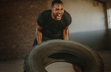 Obraz na płótnie Canvas Strong man doing heavy tire flip exercise