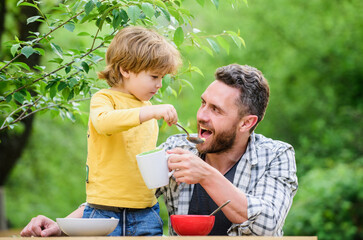 Obraz premium this is for you. healthy food and dieting. Childrens day. happy fathers day. Little boy with dad eat cereal. family dinner time. father and son eating outdoor. summer picnic. Morning breakfast
