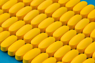 pharmacy industry produce concept of many yellow pills tablets on blue surface
