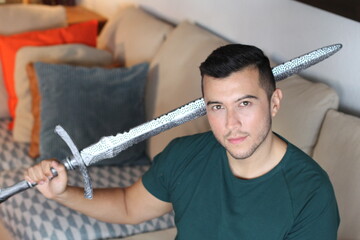 Geek holding a sword at home 