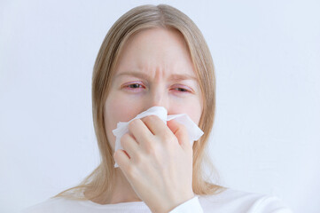 Colds and flu. Caucasian young woman sneezing into white napkin.
