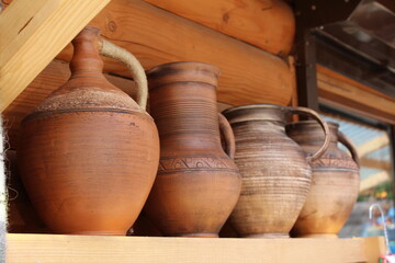 Fototapeta na wymiar Rustic large earthenware wine jugs / pots. Set of vintage jugs on a shelf isolated on a wooden background. Handmade ceramic jugs and clay pots on the market.