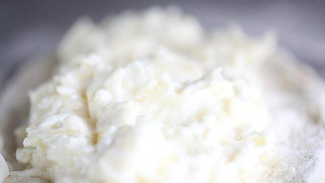 Baker prepares a pie with a cottage cheese. He puts fillings on a dough 