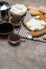 tiramisu dessert cooking - Traditional Italian Savoiardi ladyfingers Biscuits and cream in glass baking dish, coffe maker on concrete background