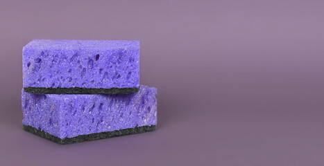 A porous purple washcloth for cleaning the apartment and washing dishes on a gray background.
