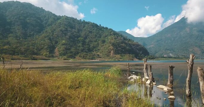 drone aerial flying over the grass towards the lake in a sunny day, Atitlan, Guatemala