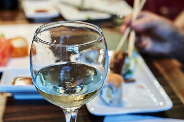 Glass with leftover white wine on the background of the table with Japanese cuisine