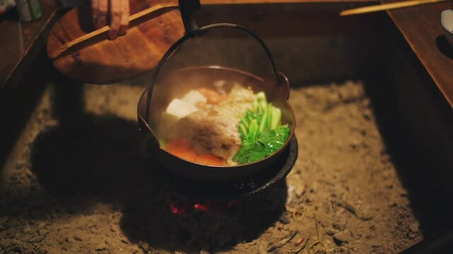 Person Lifted The Wooden Lid To Check The Delicious Hotpot Being Cooked On A Traditional Japanese v Inside The Restaurant In Wakayama, Japan. - close up shot