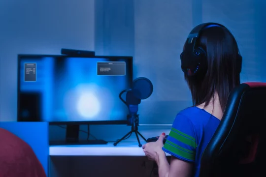 Chica gamer jugando a videojuegos con cascos, mando, micrófono, cámara y  pantalla. Photos | Adobe Stock