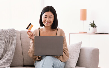 Young asian woman making purchases sitting on the couch