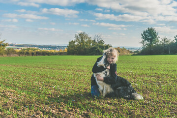 child and dog playing together in scenic field