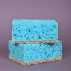 A porous blue washcloth for cleaning the apartment and washing dishes on a gray background.