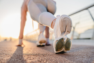 Close up cropped of athlete woman in running start pose on city street.