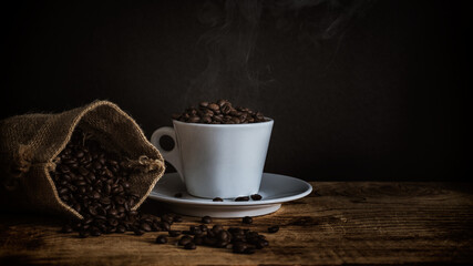 View of roasted dark coffee beans on coffee cup freshly roasted beans in jute burlap bag still life photography
