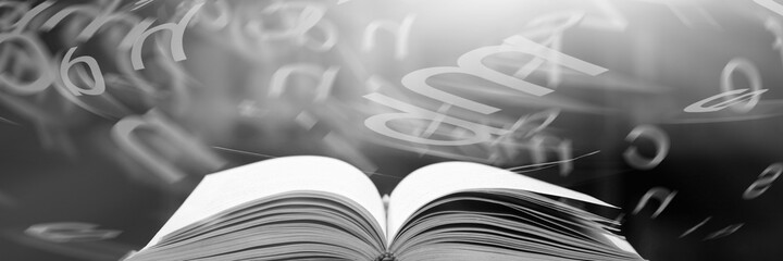 Open book on the table and english alphabet floating above the book in the library and blurred bookshelf background. education background. back to school concept.