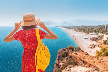 Fototapeta premium Happy female tourist looking from the height of the observation viewpoint overlooking Konyaalti beach in Antalya. Tourism and lifestyle in Turkey