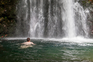 Man swims at the waterfall
