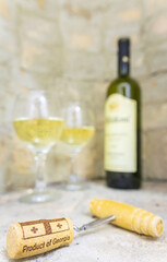 wine opener with cork in focus with blurry background of gerogian white wine bottle and to full...