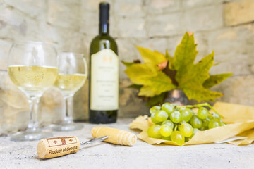 wine opener with cork in focus with blurry background of gerogian white wine bottle two full...