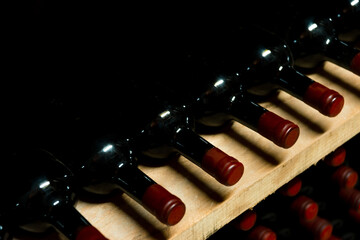 Beautiful photo of dark bottles with red wine laying underground in humidity