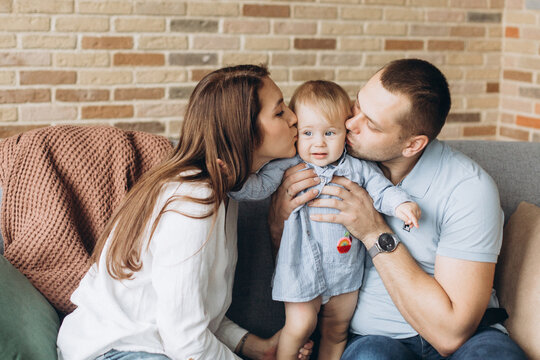 Happy family kissing little cute adorable kid. Young parents together at home