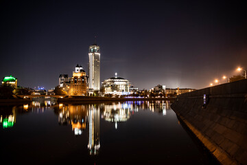 river embankment of a large metropolis at dawn with glowing lanterns reflections in the river