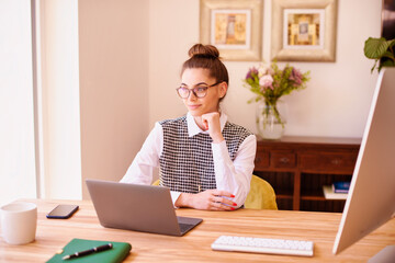 Businesswoman looking thoughtfully while sitting behind her laptop at the desk