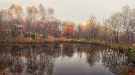 Fototapeta na wymiar Misty late fall landscape, wild lake in the autumn forest with reflection in the calm water, scenic panoramic view