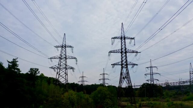 Electricity pylons bearing the power supply across a rural landscape during sunset. Selective focus.