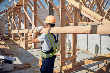 Strong young male person carrying long beam