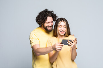Happy young couple looking at mobile phone isolated on white background