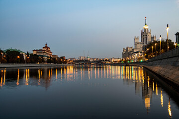 Fototapeta premium river embankment of a large metropolis at dawn with reflections in the river