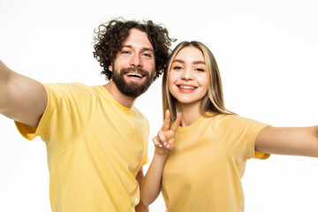 Obraz premium Funny couple showing tongues and gesturing v-sign while making selfie isolated on white background